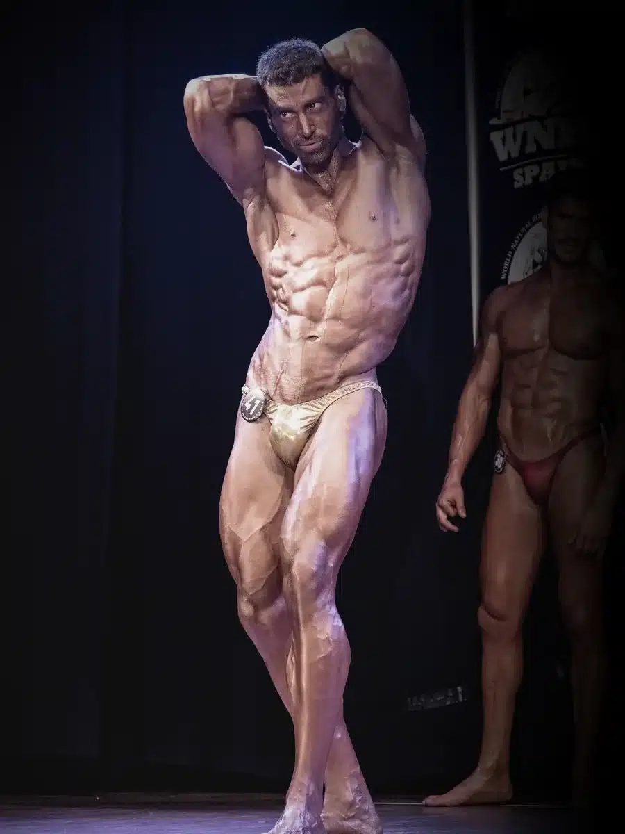 Atleta PRO de culturismo natural posando en competición